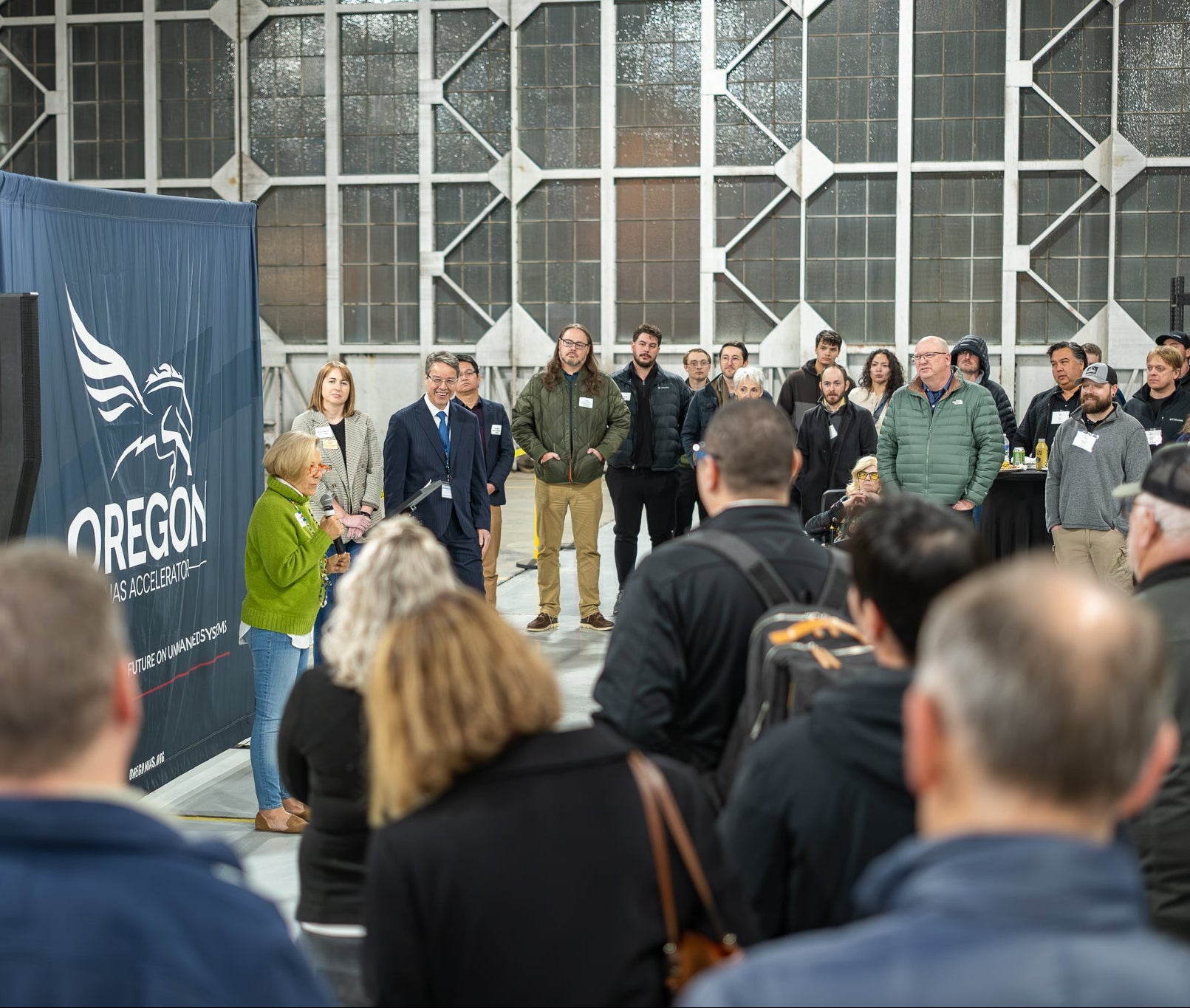 Group of people listening to a speaker with an 'Oregon' banner in the background